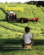 A boy sitting in the grass with a tractor.