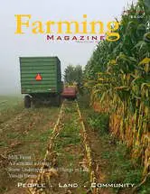 A green tractor pulling a trailer in the middle of a field.